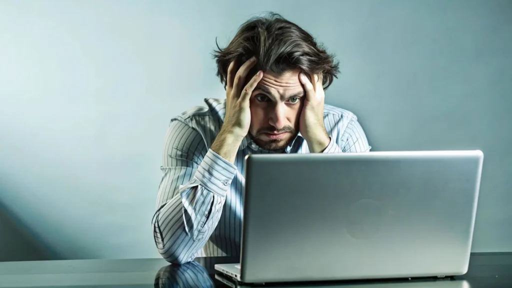 Hombre frustrado frente a un portátil por problemas técnicos o de visibilidad web.